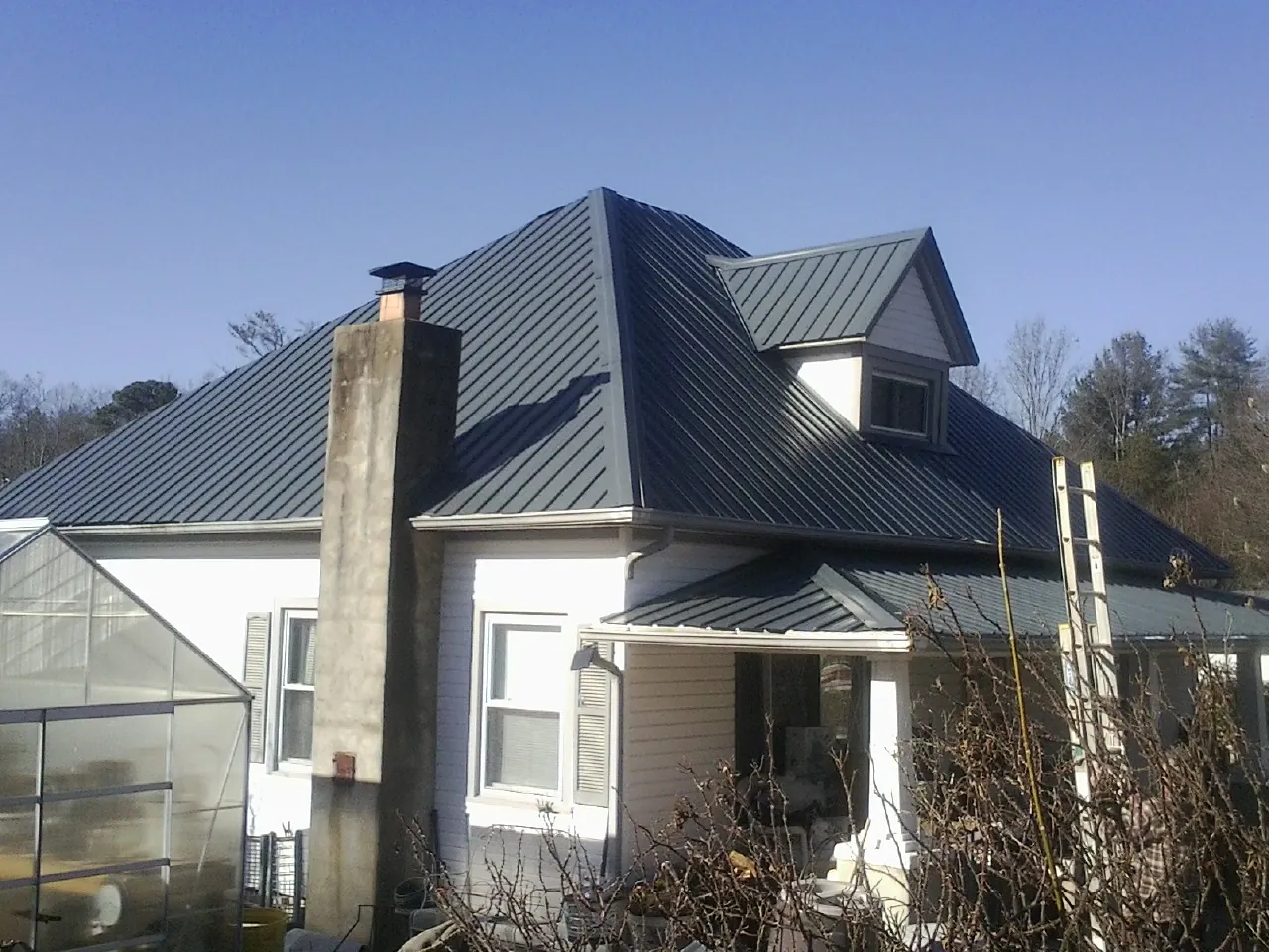 Dark blue standing seam metal roof on a white farmhouse with dormer — Slate & Tile Roof Repair by Roofing Brothers in South Hill