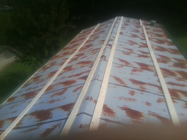 Rusted metal roof panels with new wood purlins before replacement — Storm Damage Roof Repair in South Hill by Roofing Brothers