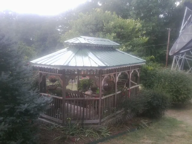 Green metal roof on a backyard gazebo surrounded by garden beds in South Hill