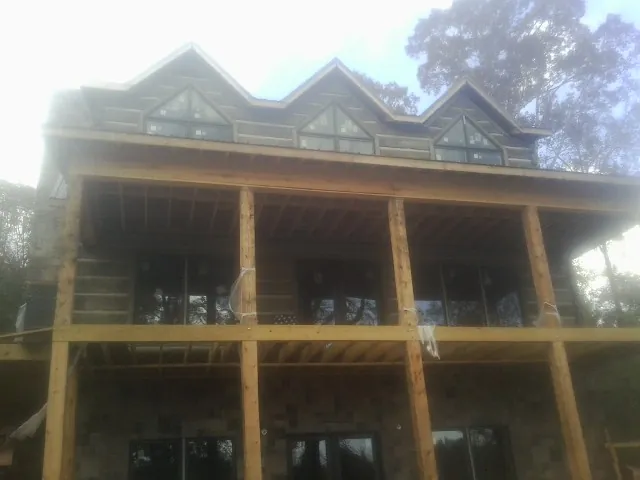 Dormers and porch framing on a large log home under construction — Roof Coating work by our crew in South Hill
