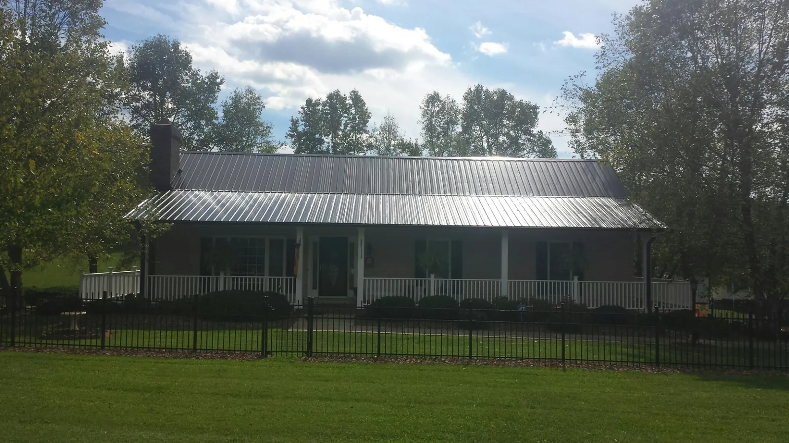Gray metal roof on a brick ranch with a full width front porch — Gutter Guard Installation work by our crew in South Hill