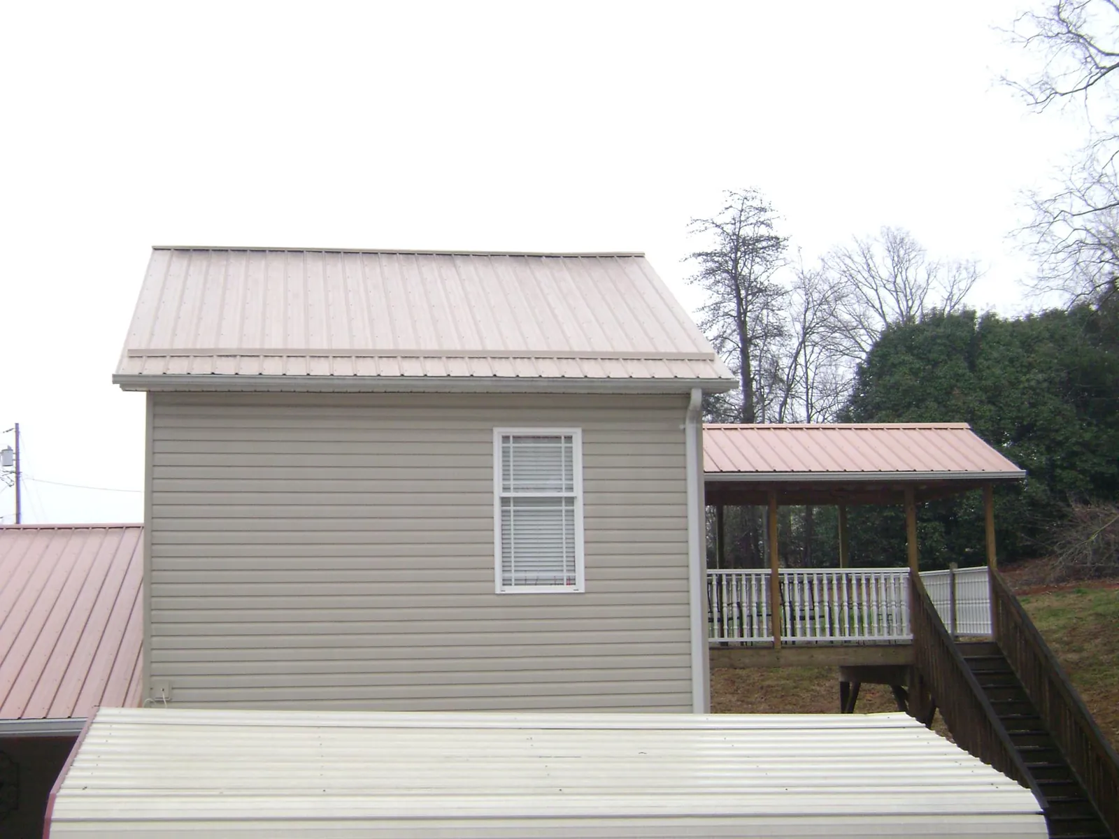 Tan metal roofs on a two story addition and attached porch, from a Roof Replacement job in South Hill